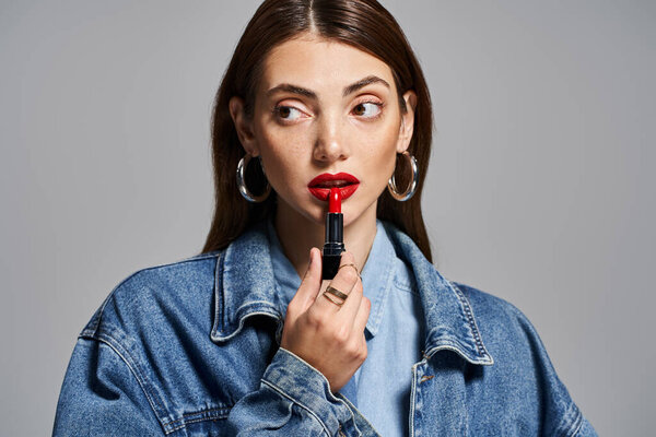 A young Caucasian woman showcases her clean skin and brunette hair, with striking red lipstick on her lips.