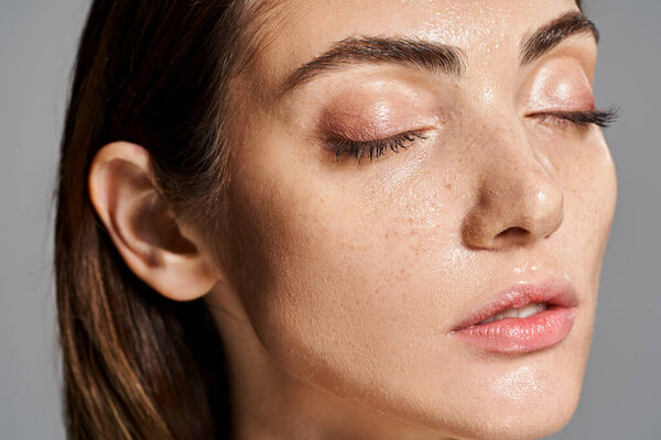 A young Caucasian woman with brunette hair peacefully closes her eyes in a serene moment of relaxation.