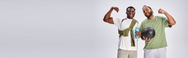sport banner, happy african american male friends holding ball and water bottle on grey backdrop clipart