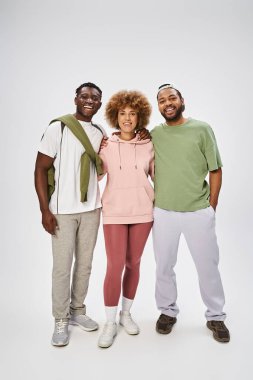 happy african american friends standing and hugging on grey background, Juneteenth celebration clipart