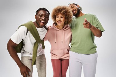excited african american friends showing thumb up, hugging on grey background, Juneteenth clipart