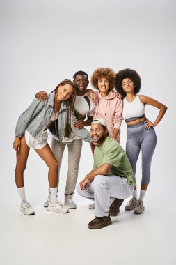 Spor giyimli neşeli Afro-Amerikan erkek ve kadınlar gri arka planda yan yana duruyorlar, Juneteenth