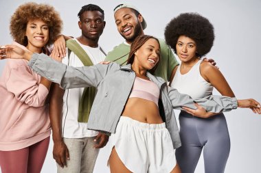 Neşeli Afro-Amerikalı kadın spor giysilerinde arkadaşlarının yanında gri arka planda gülümsüyor, Juneteenth