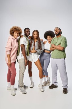 joyful african american friends in sportswear standing together on grey backdrop, Juneteenth clipart