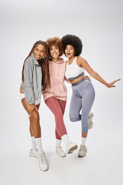 african american friends in sportswear looking at camera on grey backdrop, Juneteenth celebration clipart