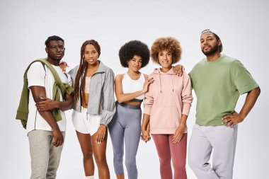 Bir grup mutlu Afro-Amerikan spor giyim sektörü gri arka planda, toplulukta birlikte duruyorlar.