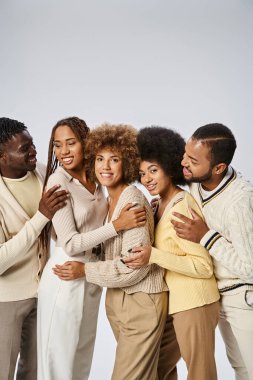Bir grup mutlu Afrikalı Amerikalı zarif giyinmiş gri arka planda sarılıyorlar, Juneteenth.