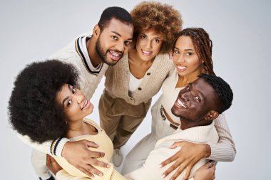 top view of happy african american people bonding and hugging on grey background, Juneteenth clipart