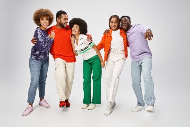Mutlu Afro-Amerikan insanları gri arka planda gülerek günlük kıyafetlerini giyerler.