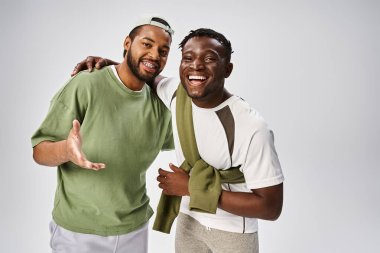 smiling african american male friends in casual wear hugging on grey background, Juneteenth clipart