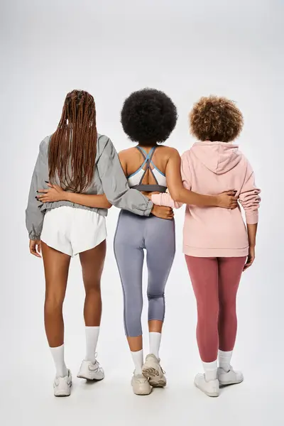 stock image back view of african american women in sportswear posing on grey backdrop, Juneteenth celebration