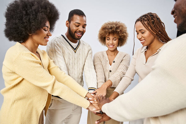 cheerful african american people stacking hands together on grey background, Juneteenth concept
