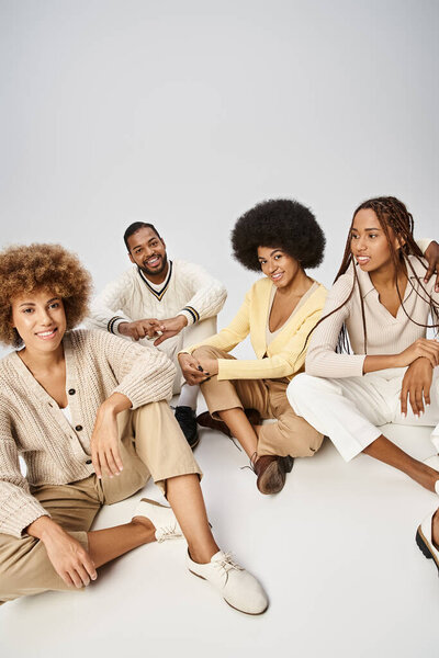 group of cheerful african american friends in casual attire sitting on grey background, Juneteenth