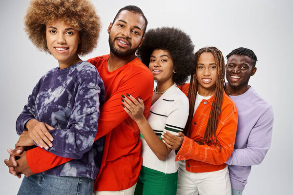 joyful african american people in casual attire hugging each other on grey backdrop, Juneteenth