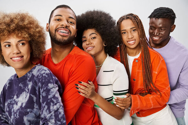 cheerful african american community in casual attire hugging each other on grey backdrop, Juneteenth