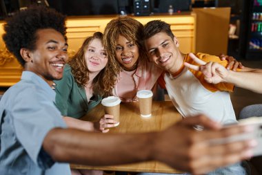 excited african american student taking selfie with happy multicultural friends in hostel cafe clipart