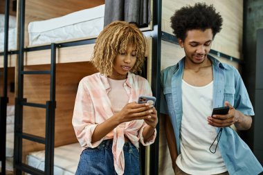 Lüks Afrikalı Amerikalı ev arkadaşları rahat öğrenci yurdunda çift katlı yatakların yanında akıllı telefonlar kullanıyorlar.