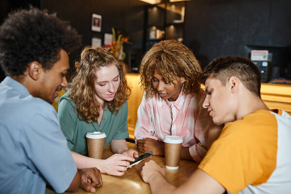 youthful woman browsing internet on smartphone near multiethnic friends in cafe of youth hostel