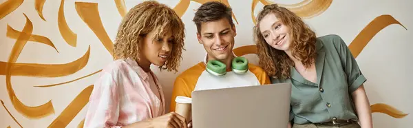 Stock image cheerful interracial women looking at laptop near student on staircase on modern hostel, banner