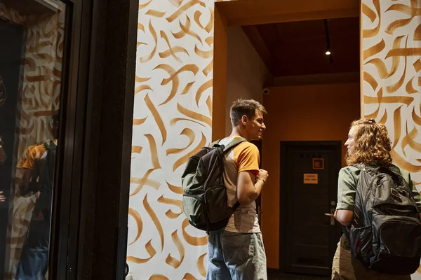 stock image back view of smiling couple of students talking in corridor of youth hostel with modern design