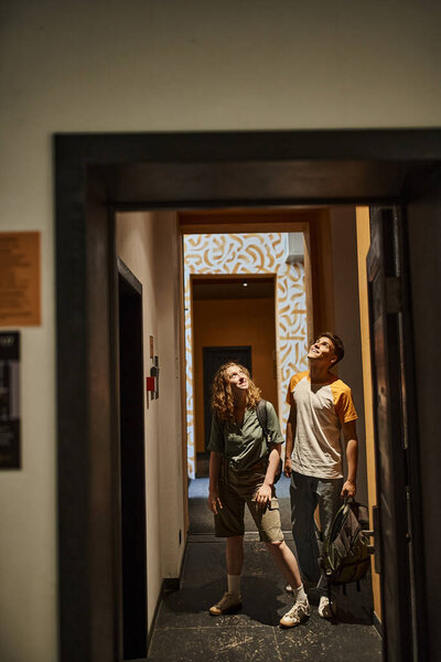 молодая и впечатленная пара, глядя на современный дизайн студенческого отеля, современных путешественников