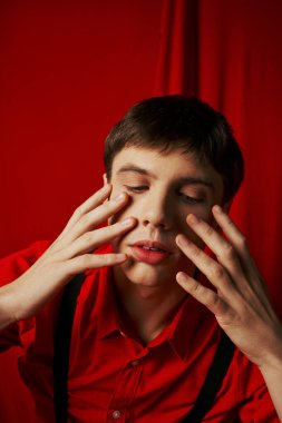 close up photo, pensive young man in shirt and suspenders touching his face on red background clipart