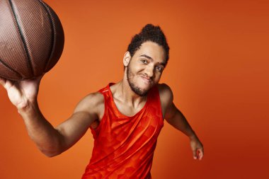 Spor giysili, neşeli Afro-Amerikan adam kollarıyla kameraya neşe içinde gülümsüyor.