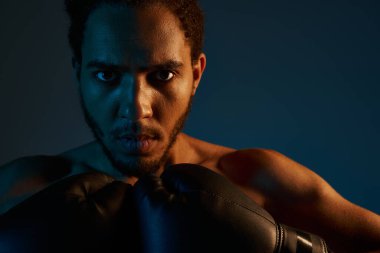 Spor giysili, neşeli Afro-Amerikan adam kollarıyla kameraya neşe içinde gülümsüyor.