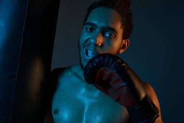 Spor giysili, neşeli Afro-Amerikan adam kollarıyla kameraya neşe içinde gülümsüyor.