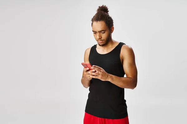 Kjekk Afrikansk Amerikansk Idrettsutøver Ser Smarttelefonen Hans Grå Bakgrunn Online – stockfoto
