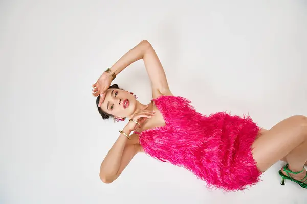 豪華なピンクの毛皮のドレスで彼女の顔に触れる素晴らしいブルネット女性のスタジオの肖像画 — ストック写真