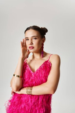 Pembe elbiseli neşeli genç bayanın portresi gri arka planda yanağına dokunuyor.