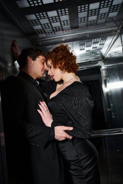 Zarif siyah elbiseli neşeli sevgili asansörde sarılıyorlar, seksi çift.