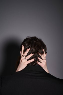 Siyah takım elbiseli bir adamın gri arka planda sevgilisine sarılışının arka planı. Seksi bir çift.