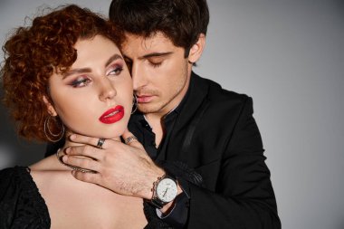 Takım elbiseli yakışıklı adam, çekici kız arkadaşını sıkı sıkı tutuyor. Kırmızı rujlu, seksi çift.
