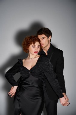Çekici takım elbiseli çekici adam kameraya bakarken çekici kız arkadaşına sarılıyor, seksi çift.