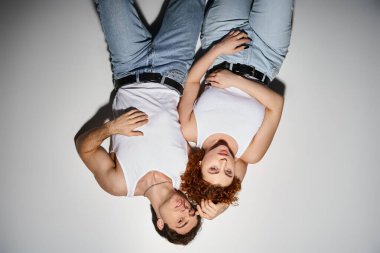 Çekici bir erkek ve kadın, kot pantolonlar içinde yerde yatıp kameraya bakıyorlar, seksi bir çift.