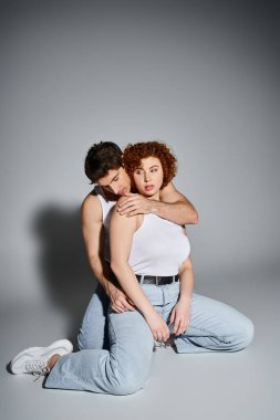 Kot pantolonlu çekici bir adam ve kadın yerde birlikte oturuyor ve sıcak, seksi bir çift gibi sarılıyorlar.