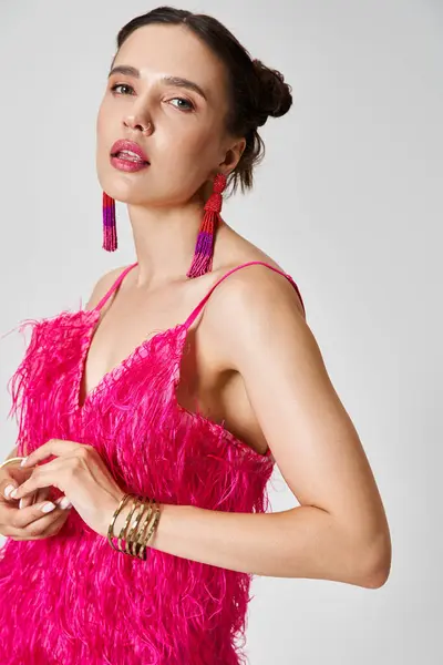 グレーの背景に対して胸に触れるファッショナブルなピンクの服に自信を持った女性 — ストック写真
