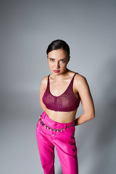 Fabulous brunette woman in trendy red top and fancy jewelry looking confident isolated on grey