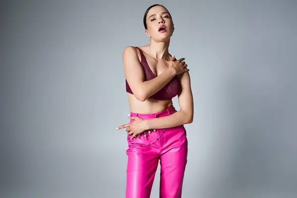 stock image Fashionable brunette in pink trousers and dark red top, wearing stylish jewelry, hands on her body