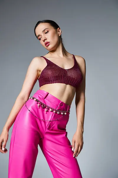 stock image Brunette woman wearing knitted bordeaux top and stylish pink pants looking away, studio setting