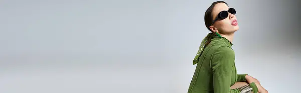 stock image Side view of lady in total green outfit wearing sunglasses sitting and showing tongue, banner