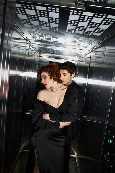 sexy appealing couple in elegant black dress and suit hugging lovingly in elevator after date