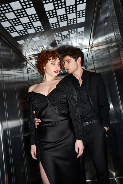 sexy attractive couple in elegant black dress and suit hugging lovingly in elevator after date