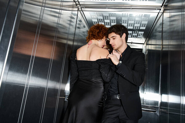 good looking couple in elegant black dress and suit hugging lovingly in elevator after date
