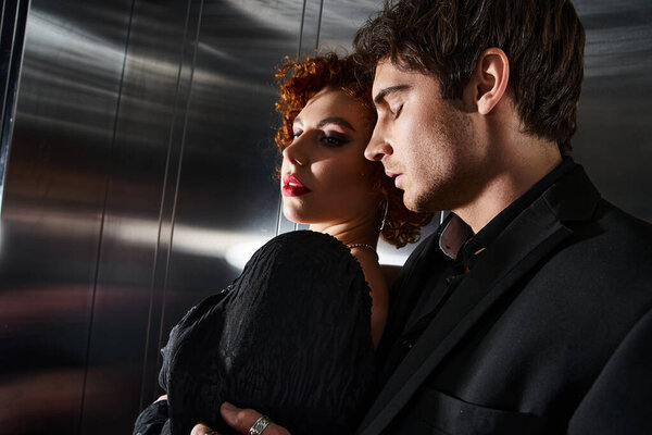 привлекая сексуальную пару в элегантном черном платье и обнимаясь с любовью в лифте после свидания