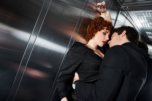 страстная сексуальная пара в элегантном черном платье и костюме, обнимающаяся с любовью в лифте после свидания