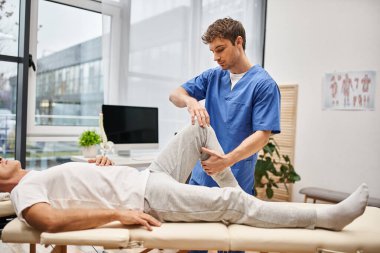 Mavi cüppeli yakışıklı doktor olgun hastasının hastanede tedavi olmasına yardım ediyor.