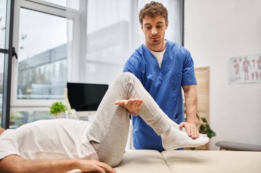 Mavi cüppeli yakışıklı doktor olgun hastasının hastanede tedavi olmasına yardım ediyor.